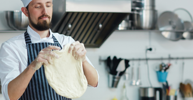 Homem abrindo massa de pizza com as mãos